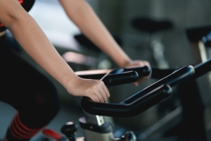 Crop picture of close up hand of woman exercising on a bicycle in her home gym.