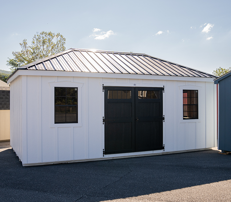 White shed with a metal roof and black door.