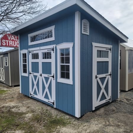 Shed with blue siding, white trim, 3 windows and 3 doors