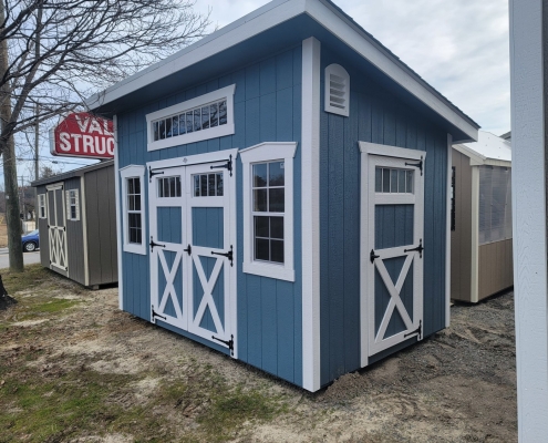Shed with blue siding, white trim, 3 windows and 3 doors